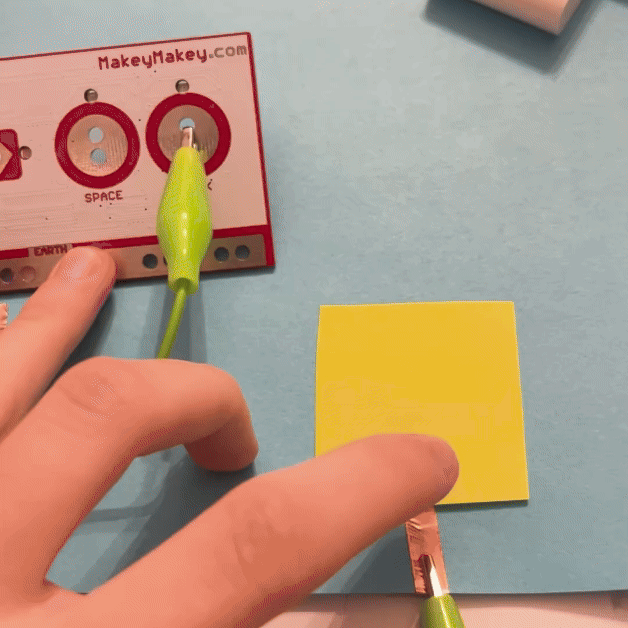 Pressing down on the sticky note activates the MakeyMakey.